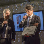 Party di Natale 2015 Allied International: Due uomini al microfono durante l'evento. Commemorazione e celebrazione.