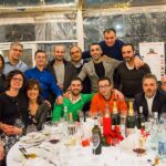 Festa di Natale 2016 Allied International. Gruppo di persone sorridenti a tavola, bottiglie di vino. 035.jpg