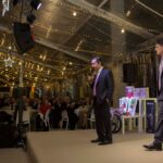 Festa di Natale 2017 Allied International: oratore sul palco con pubblico. Atmosfera natalizia.