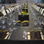 Tavolo imbandito per Christmas Party 2019 Magazzino Allied International. Calici, decorazioni natalizie, menu eleganti.